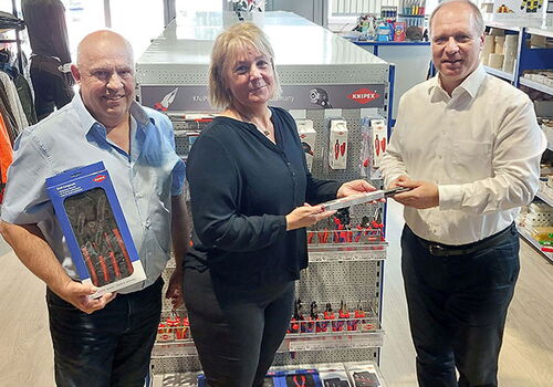 Drei Personen mit Werkzeugen in einem Geschäft.