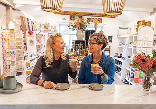 Zwei Frauen trinken Kaffee in einem gemütlichen Laden.