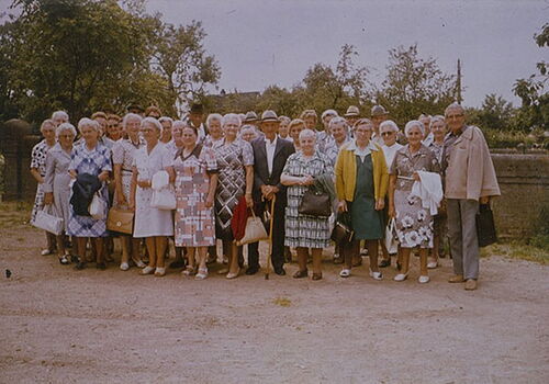 Gruppe älterer Menschen posiert draußen für ein Foto.