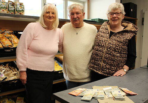 Drei Personen in einem Geschäft zeigen eine Spende von Banknoten.