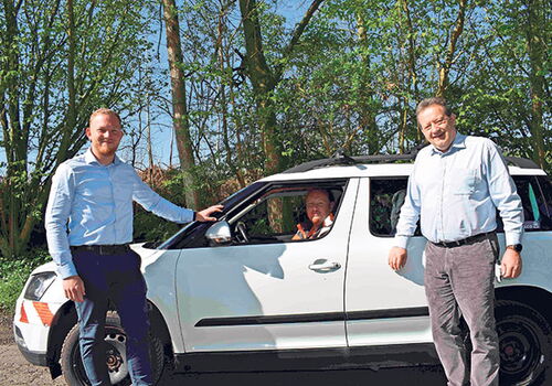 Drei Männer bei einem Auto im Kontext des Straßenkatasters.