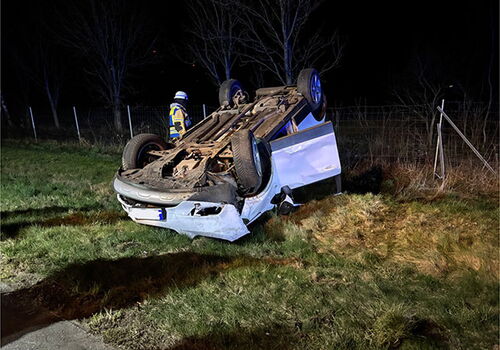 Auto nach Unfall auf dem Dach am Straßenrand liegend.