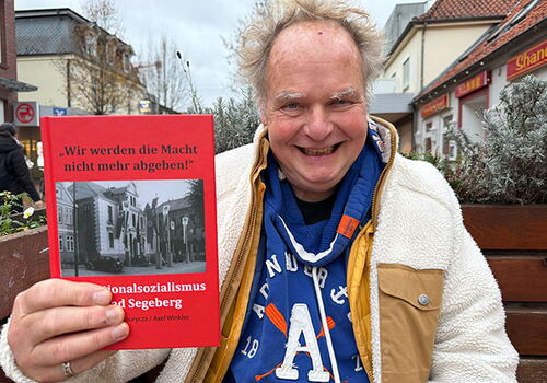 Mann hält Buch über Nationalsozialismus in Bad Segeberg.