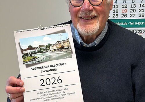 Mann hält Kalender für 2026 mit historischem Foto.