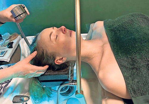 Frau erhält entspannende Kopfhautmassage im Spa.