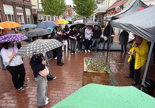 Menschen mit Regenschirmen bei einer Veranstaltung im Freien.