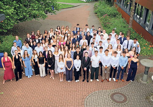Große Gruppe von Schülern posiert draußen für ein Foto.