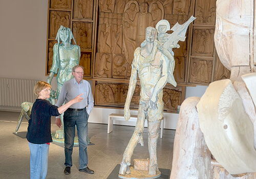 Zwei Personen betrachten Skulpturen in einer Galerie.