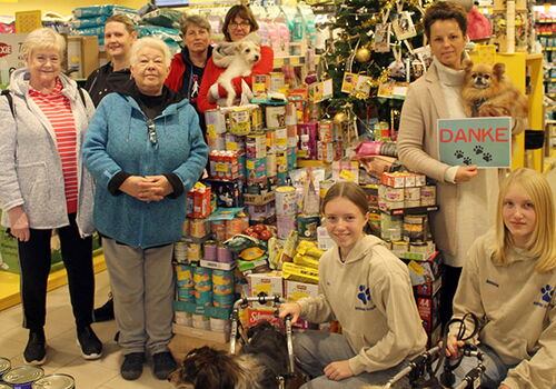 Gruppenfoto in einem Tierbedarfsgeschäft mit Spendenstapel.
