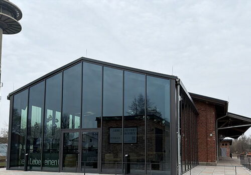 Modernes Glasgebäude neben älterem Backsteingebäude.