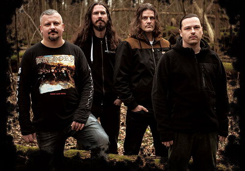 Vier Männer stehen in einem Wald und blicken ernst.