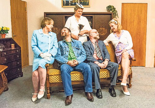 Fünf Personen auf einem Sofa in einem Wohnzimmer.