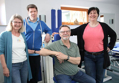 Vier Menschen in einem Fitnessstudio lächeln in die Kamera.