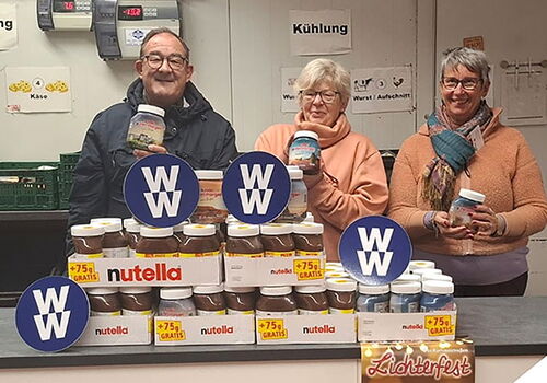 Drei Personen posieren mit Gläsern in einem Geschäft.