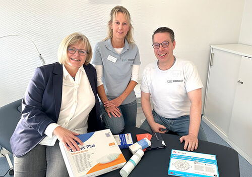 Drei Personen mit medizinischen Produkten am Tisch.