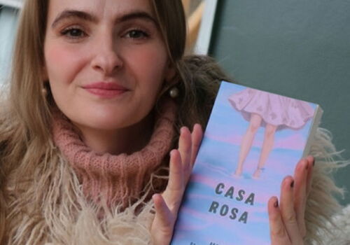 Frau hält ein Buch mit dem Titel 'Casa Rosa'.