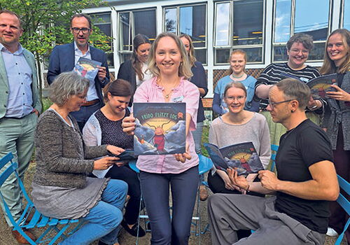 Gruppe von Menschen mit Buch vor Gebäude