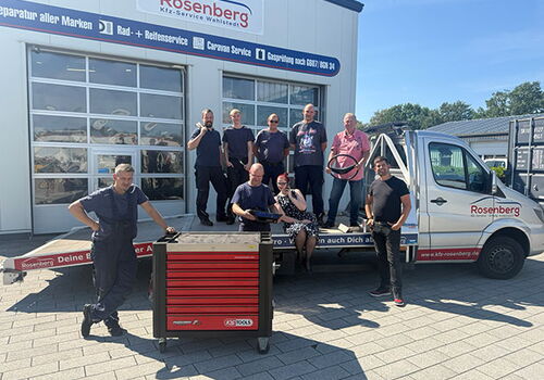 Gruppe von Menschen vor einem Werkstatt-Lkw mit Werkzeugkasten.