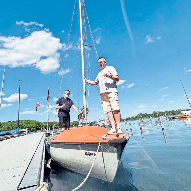 Bootstaufe am sonnigen Tag im Hafen Männer bei Bootstaufe in sonnigem Hafen