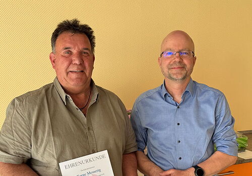 Zwei Männer mit Urkunde und Auszeichnung.