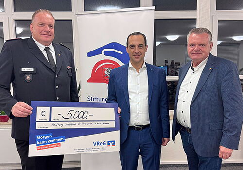 Drei Männer halten einen Scheck über 5000 Euro.