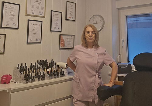 Frau in rosa Arbeitskleidung in einem zertifizierten Nagelstudio.