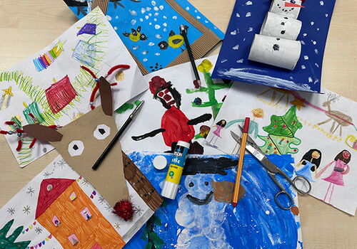 Bunte Kinderzeichnungen und Bastelarbeiten auf einem Tisch.