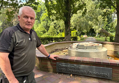 Mann steht vor einem Gedenkstein in einem Park.