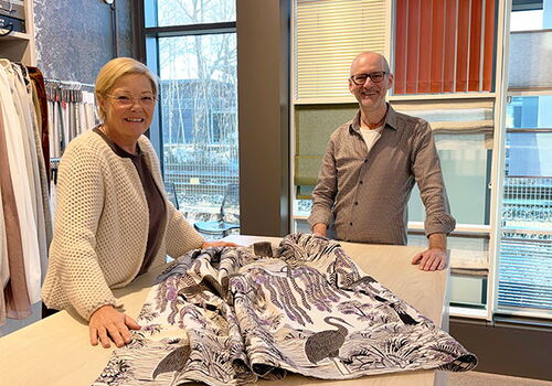 Zwei Personen neben dekorativem Stoffmuster im Geschäft