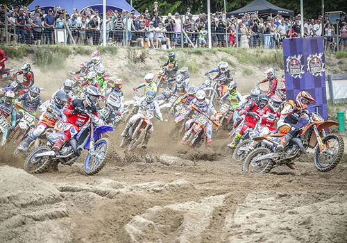 Motocross-Rennen im Sand mit vielen Fahrern und Zuschauern.