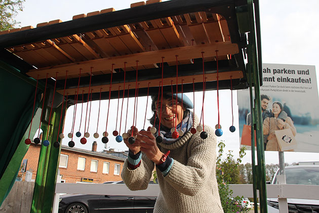 Die Straßenkünstlerin Monika Mayne  spielt auf einem selbstgebauten Ziehlophon. In der vergangenen Woche trat sie in der Bad Segeberger Fußgängerzone auf. Foto: ohe