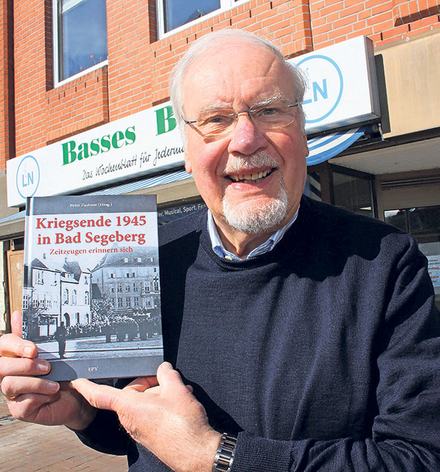 Peter Zastrow hält ein Buch vor einem Gebäude