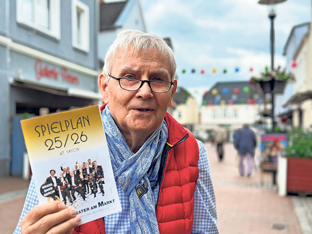 Mann hält Spielplan in einer Fußgängerzone.