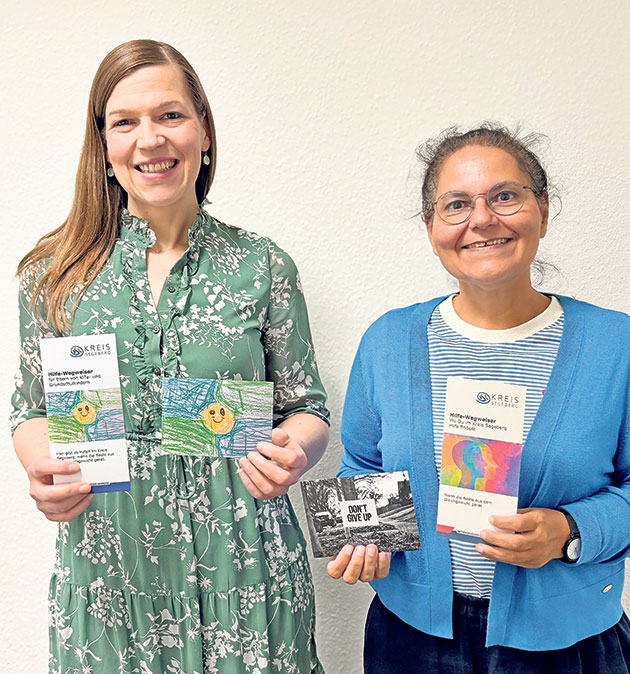Frauen präsentieren Info-Materialien. Zwei Frauen halten Prospekte und Karten.