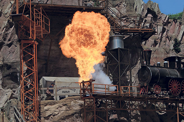 Explosion neben einer alten Lokomotive in felsiger Umgebung.