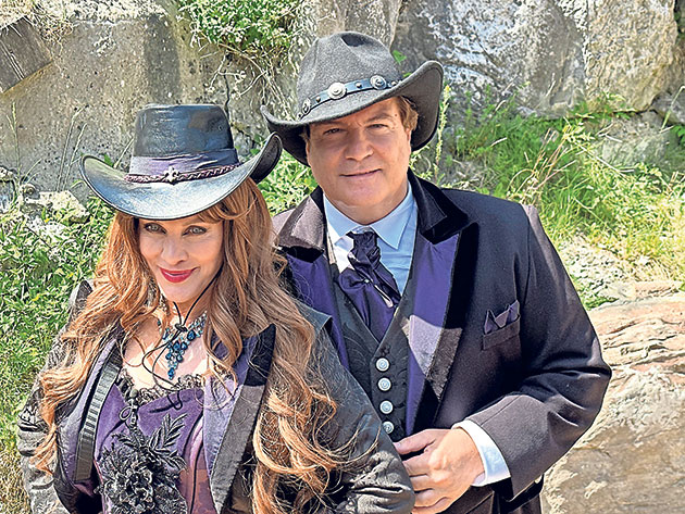 Zwei Personen in eleganten Western-Outfits im Freien.