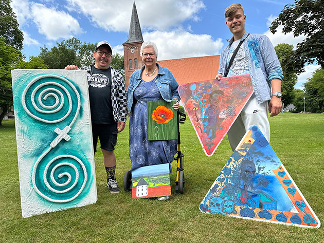 Kunst im Freien mit Gemälden dreier Personen Drei Menschen mit bunten Gemälden im Freien.