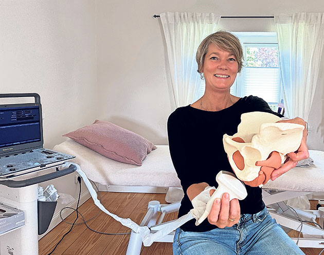 Frau mit Beckenmodell in Behandlungszimmer Frau hält ein Modell des Beckens in einer Arztpraxis.