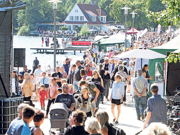 Menschenmenge bei einem Outdoor-Event an einem See.