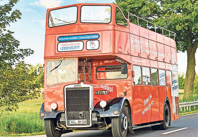 Historischer roter Doppeldeckerbus unterwegs Roter Doppeldeckerbus auf einer Landstraße.