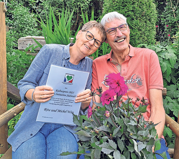 Paar auf Bank mit Blumen und Urkunde im Garten