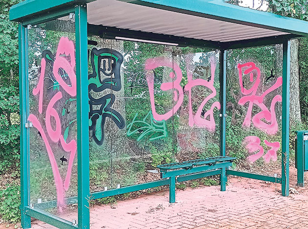 Bushaltestelle mit Graffiti auf Glaswänden.