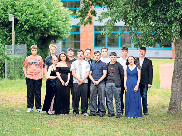 Gruppe von Jugendlichen steht in formeller Kleidung im Freien.