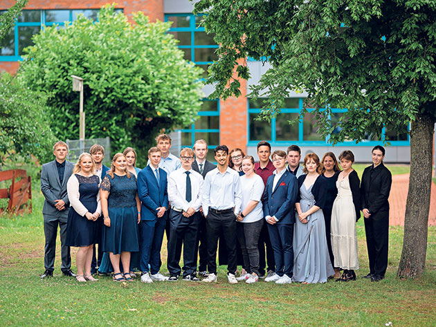 Gruppenfoto vor dem Gebäude Gruppe junger Menschen posiert draußen vor einem Gebäude.