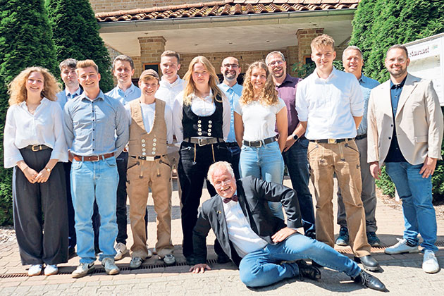 Gruppe von 14 Personen posiert lächelnd am Eingang.