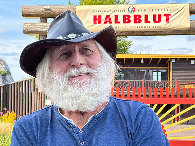 Mann mit Cowboyhut vor Halblut-Plakat.