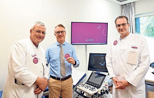 Ärzte im Untersuchungsraum Drei Ärzte in einem Untersuchungsraum mit medizinischem Gerät.