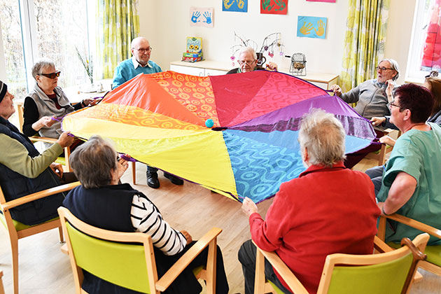 Senioren spielen mit einem bunten Schwungtuch im Kreis