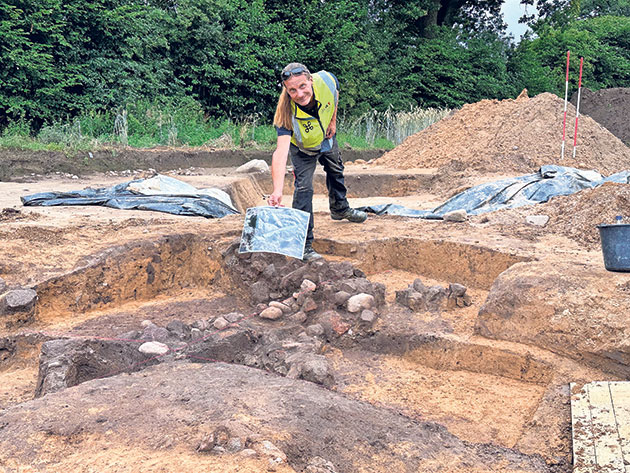 Archäologe zeigt Funde auf archäologischer Ausgrabung.