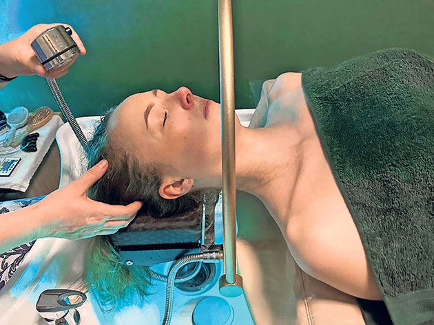 Frau erhält entspannende Kopfhautmassage im Spa.